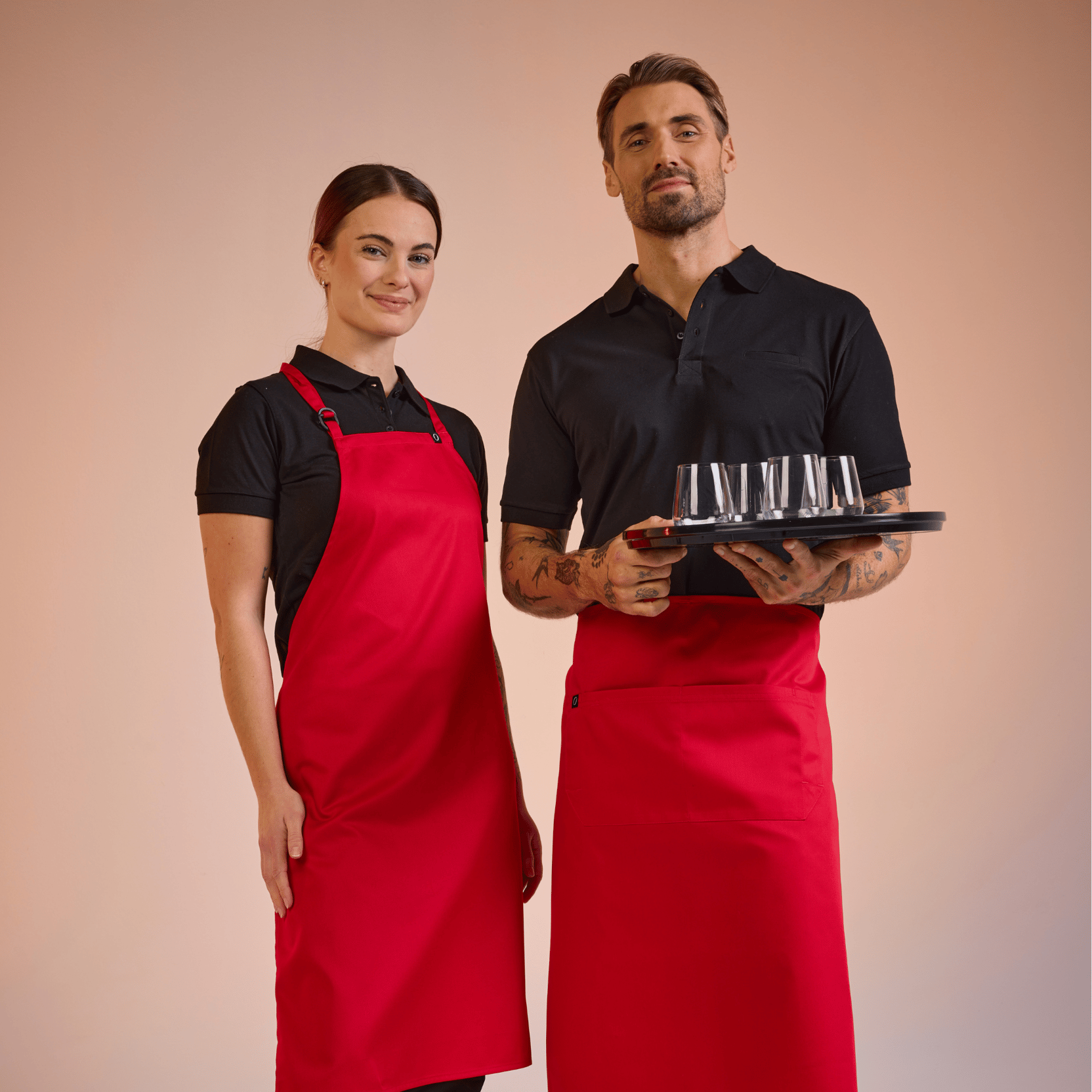 Kvinde og mand i serveringstøj fra South West med røde forklæder – klikbar link.