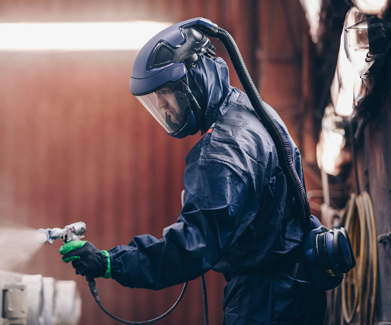 SUndströmin ja Båstad-konsernin logot, taustalla hengityssuojainta käyttävä mies