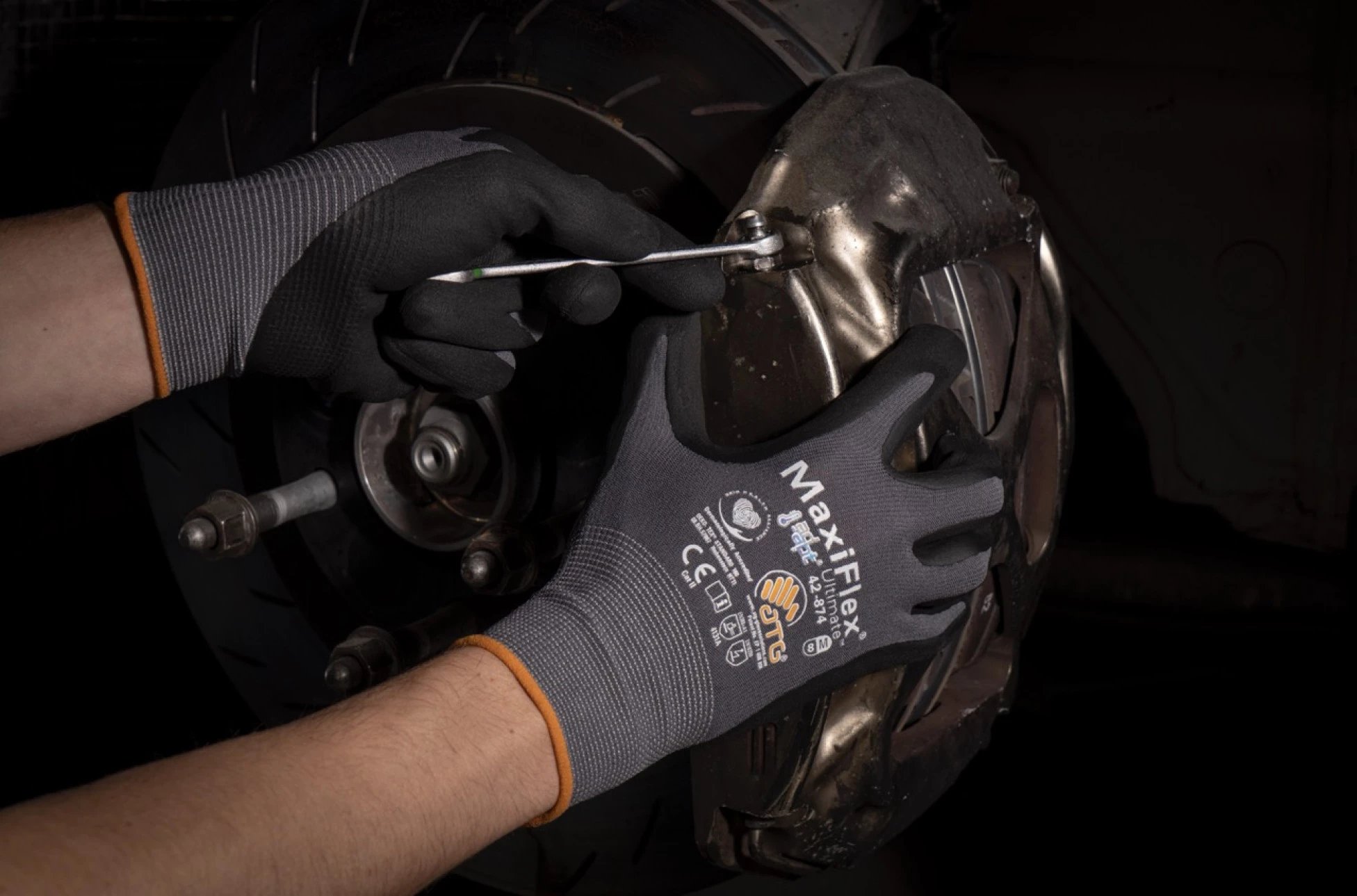 Person mit ATG MaxiCut Handschuhen schleift Metall mit einem Winkelschleifer – Funken fliegen in einer Werkstattumgebung.