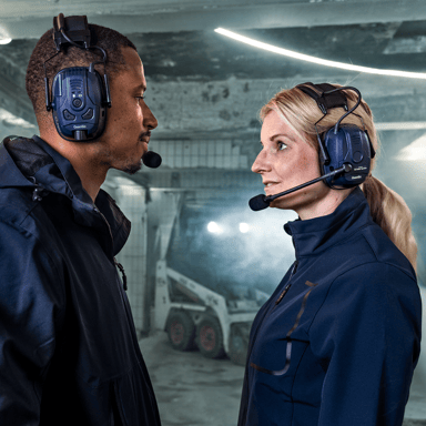 Zwei Modelle, die sich gegenüberstehen, tragen ihren eigenen Gehörschutz in einer industriellen Umgebung