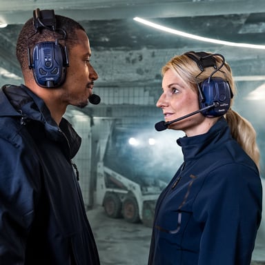 Zwei Modelle, die sich gegenüberstehen, tragen ihren eigenen Gehörschutz in einer industriellen Umgebung