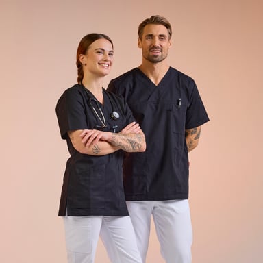 Mitarbeiter im Gesundheitswesen in Pflegekleidung aus dem South West – schwarze Tuniken mit weißen Hosen, entworfen für Komfort und Funktion. Klicken Sie auf den Link, um mehr über South West Pflege zu erfahren.