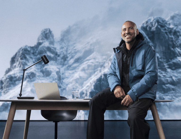 To personer i vinterjakker står med kaffekopper ved en kaffemaskin. Bak dem ser man et snødekt fjellandskap og et skrivebord. Klikkbar lenke til Matterhorn-produktene.