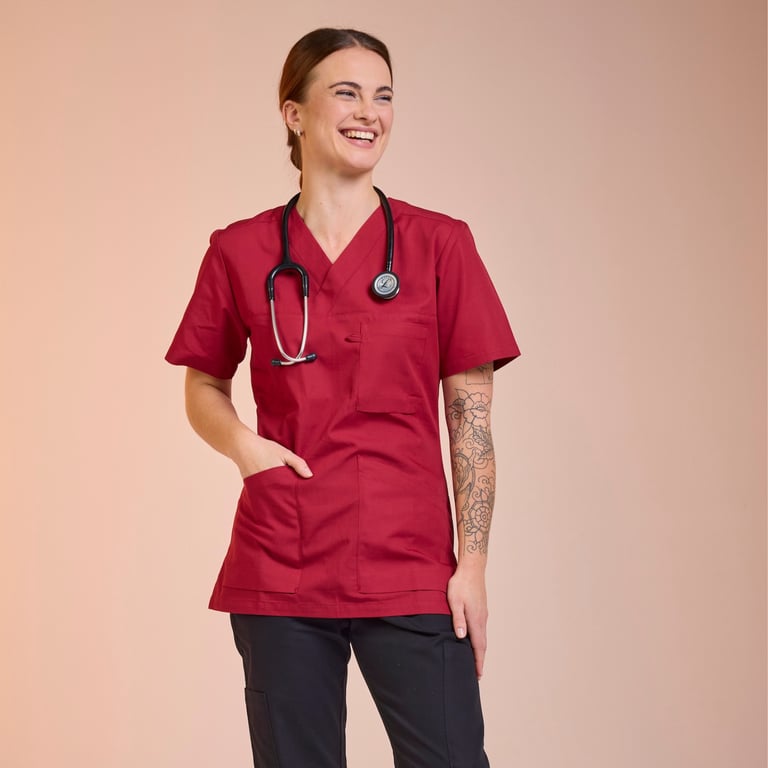 Woman in red care tunic from South West – workwear with high quality and certified durability.