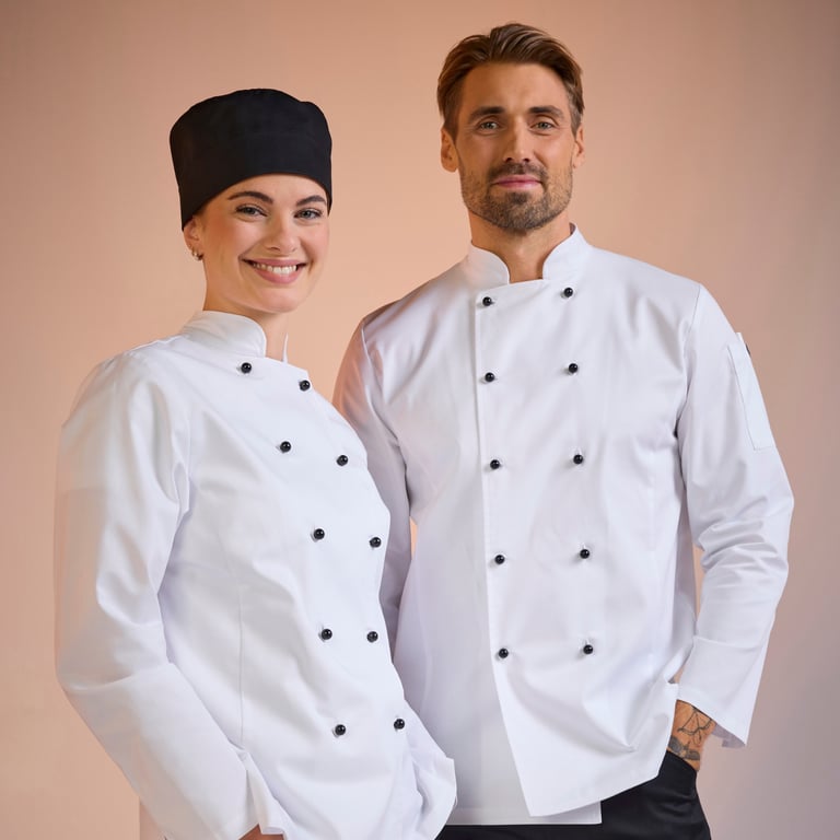Kvinde og mand i klassiske hvide kokkejakker fra South West – funktionelt tøj der giver et professionelt udtryk i restaurantkøkkenet.
