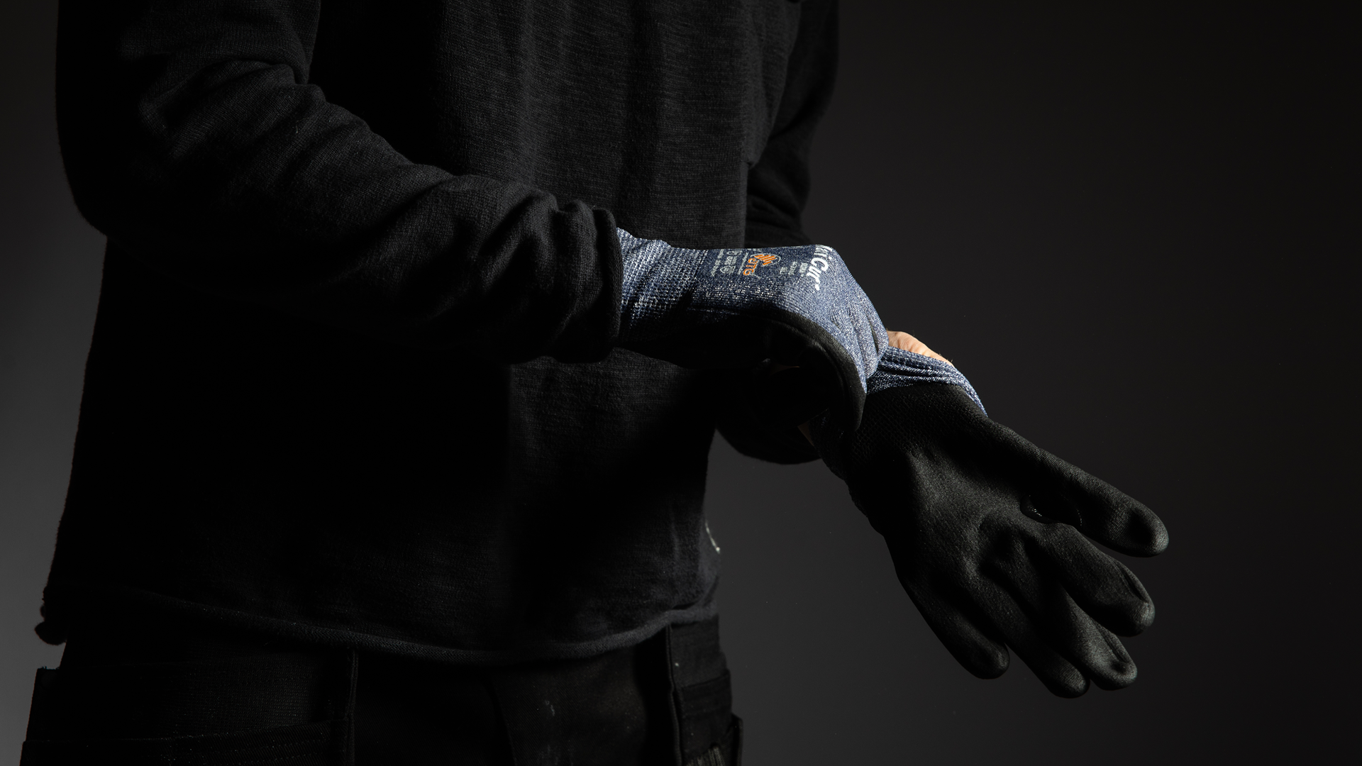 Mörk bild på häner som träder på ett par arbetshandskar