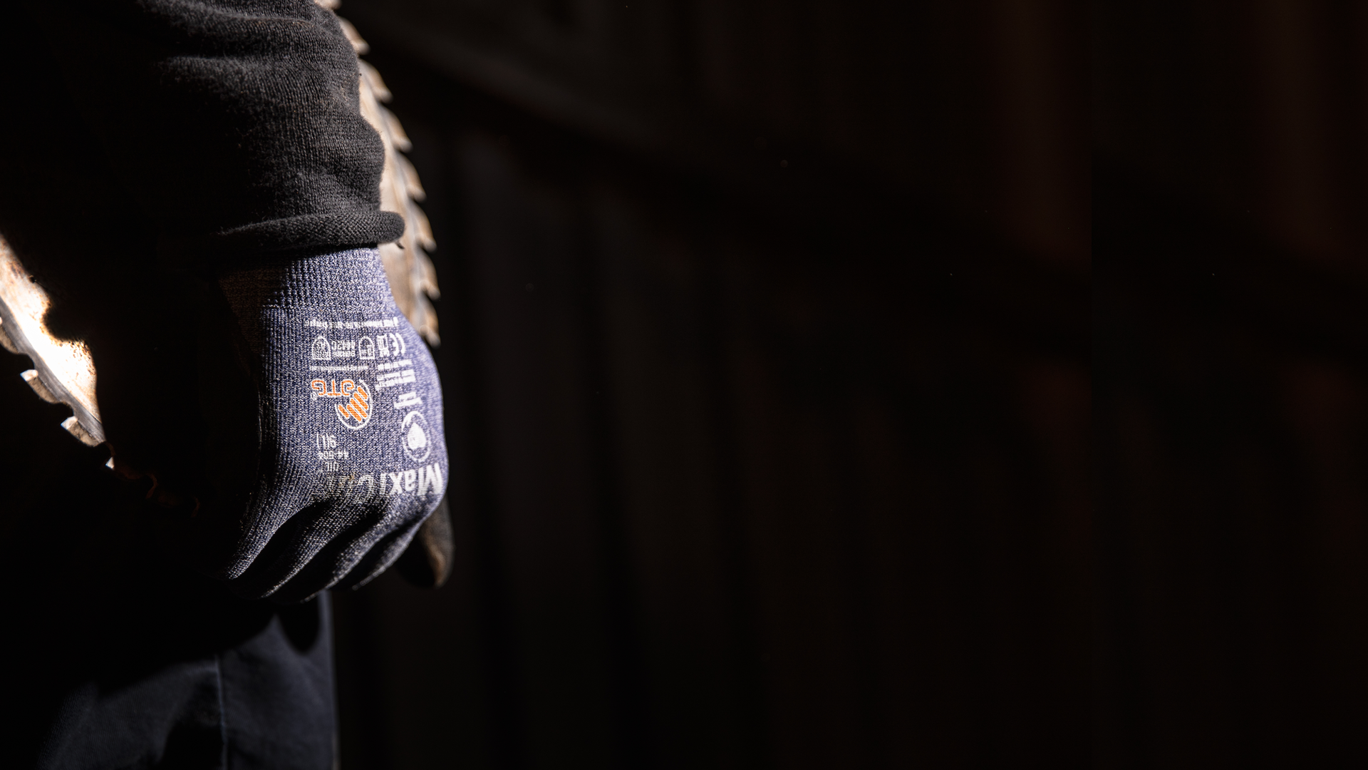 Mörk bild på hand iklädd handske som bär på vasst föremål