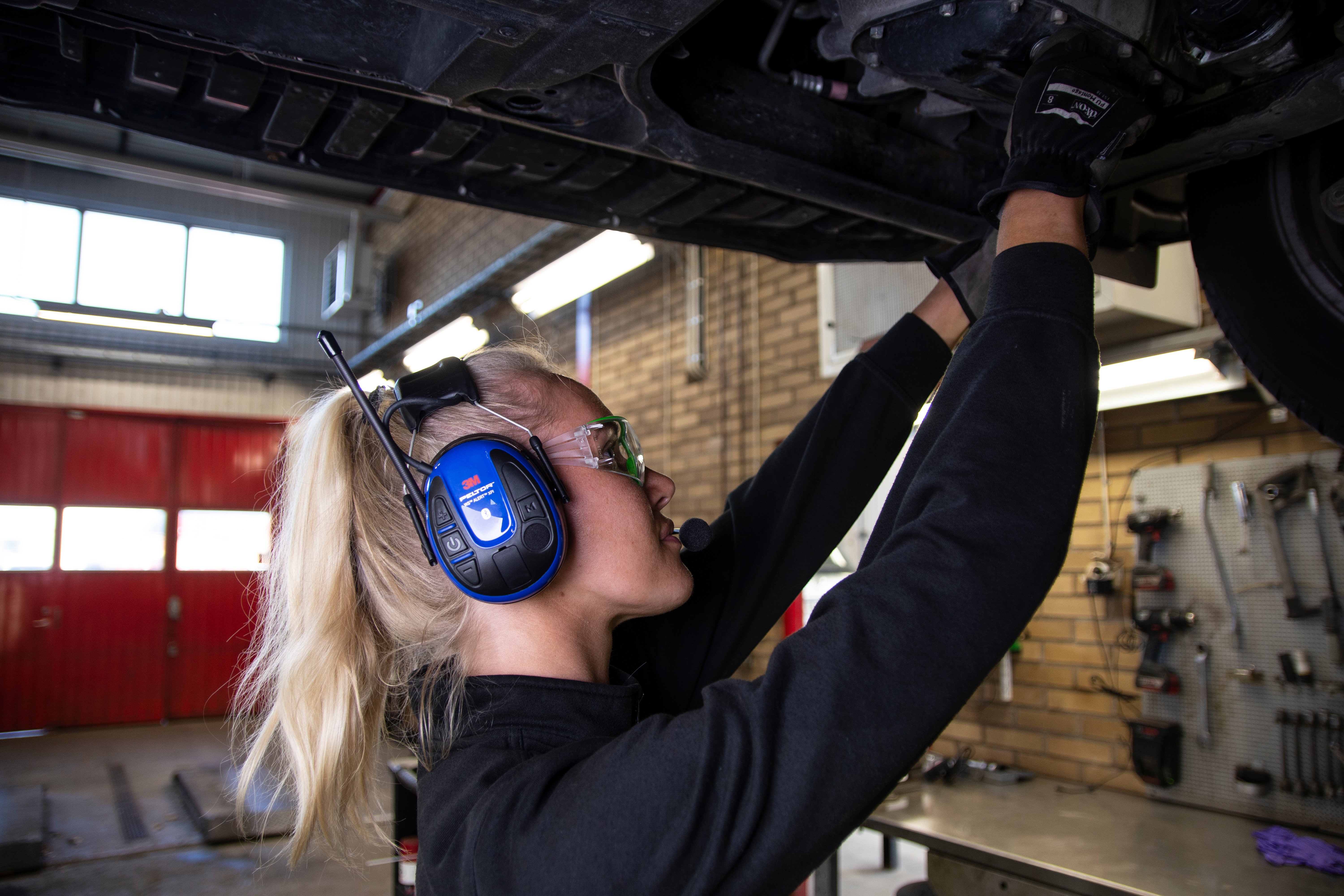 Kvinna monterar bil iklädd skyddsglasögon och hörselskydd från 3M