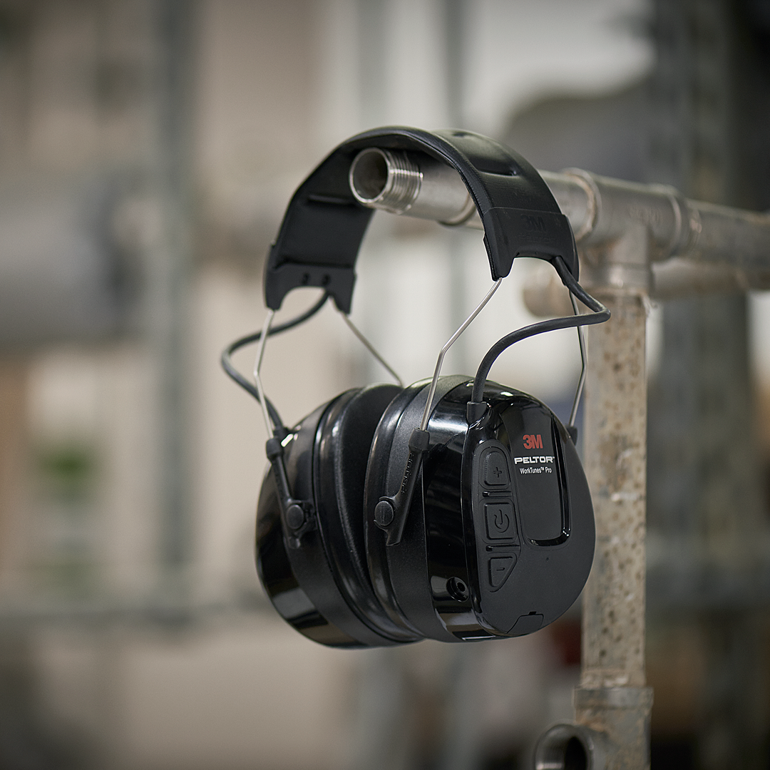 Ett par hörselkåpor från 3M som hänger på järnrör i en industriell miljö