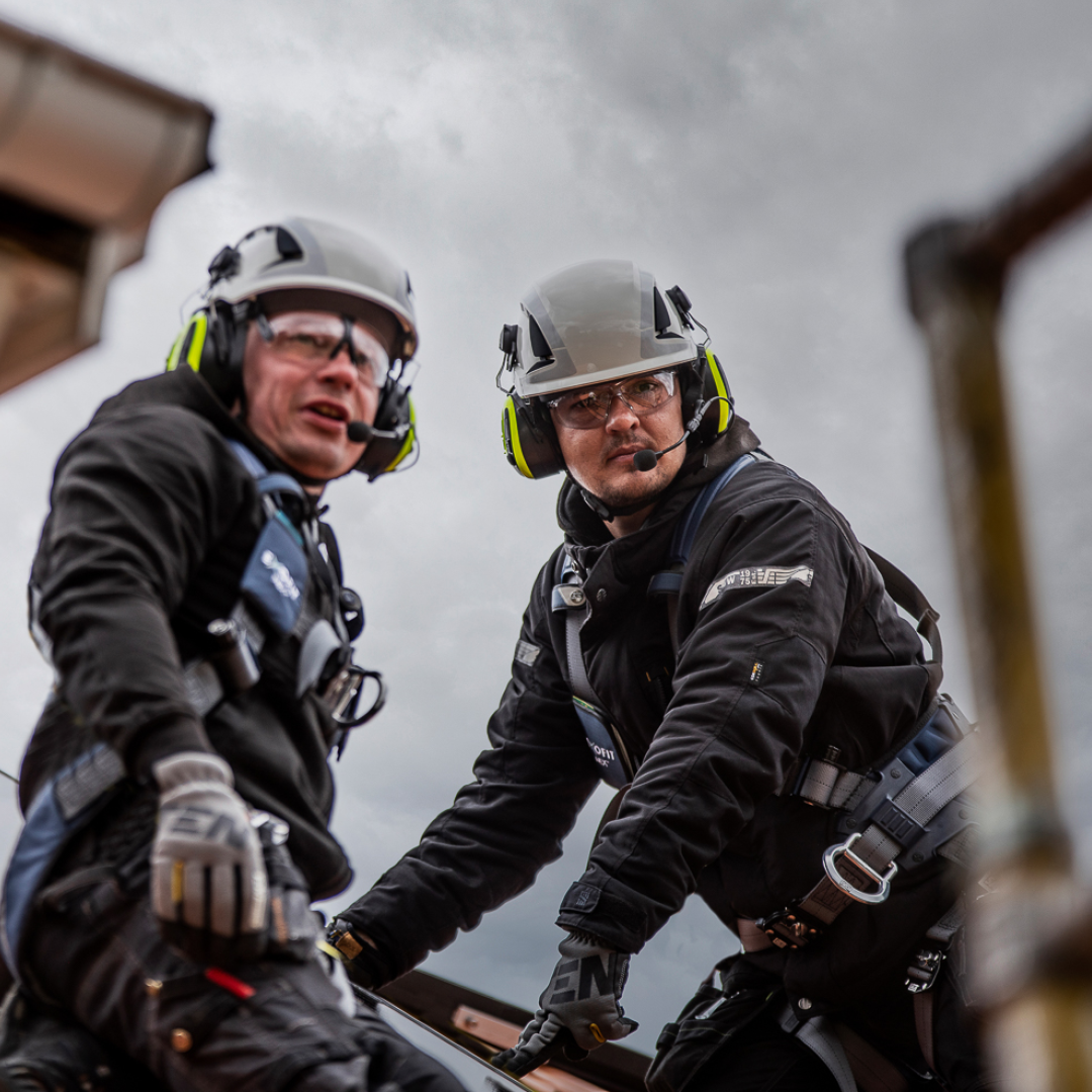 Två arbetare upp på ett tak iklädda skyddshjälmar från 3M