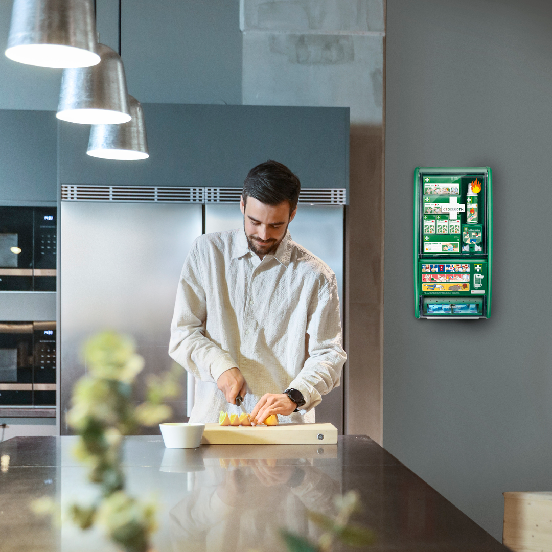 Mann in der Kantine, im Büro mit Erste-Hilfe-Station an der Wand
