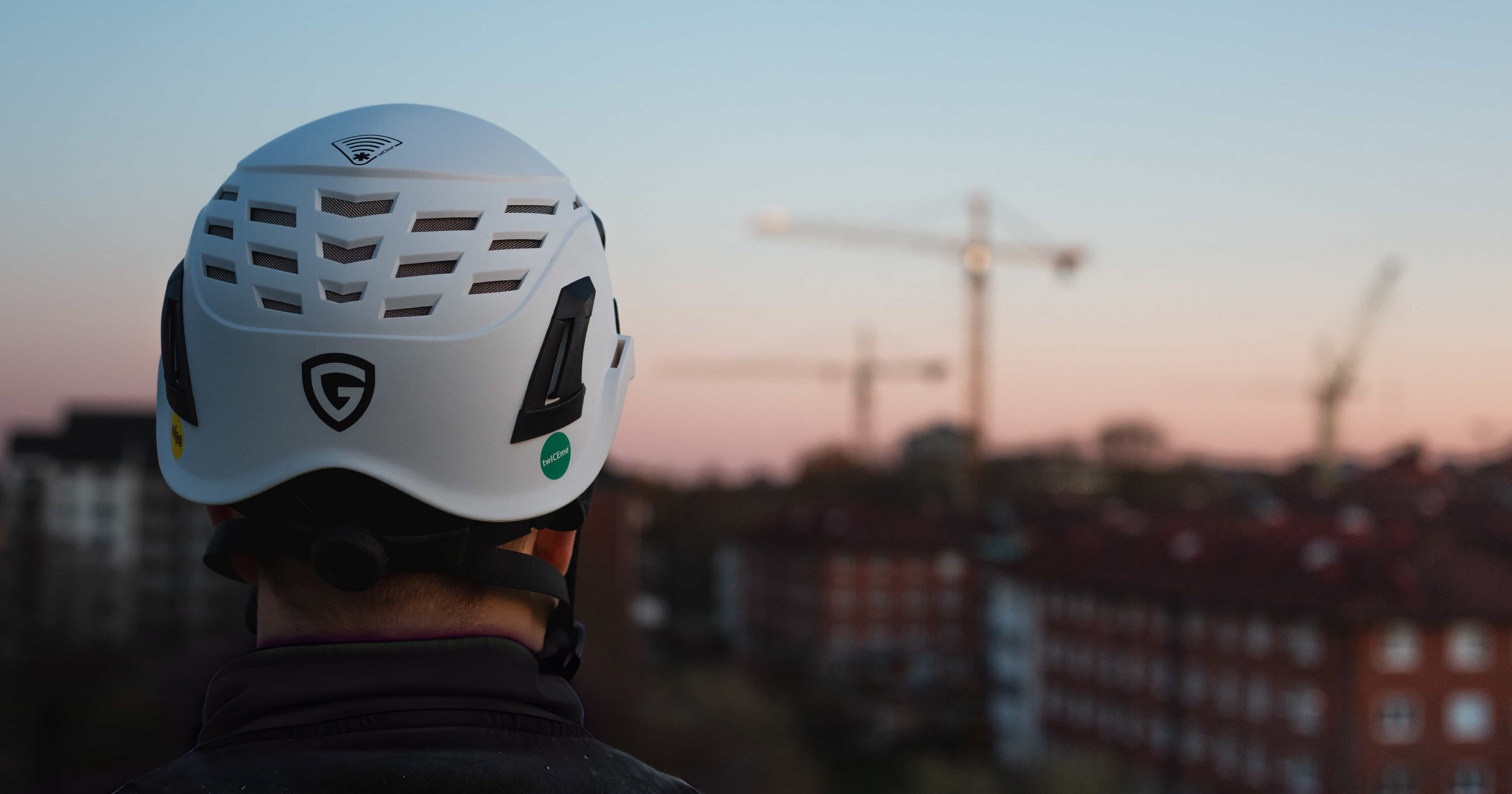 Person med skyddshjälm från Guardio sedd bakifrån, utrustad med Twiceme-logotyp och NFC-symbol på hjälmens ovansida, vilket indikerar var den digitala Twiceme-sensorn är placerad.