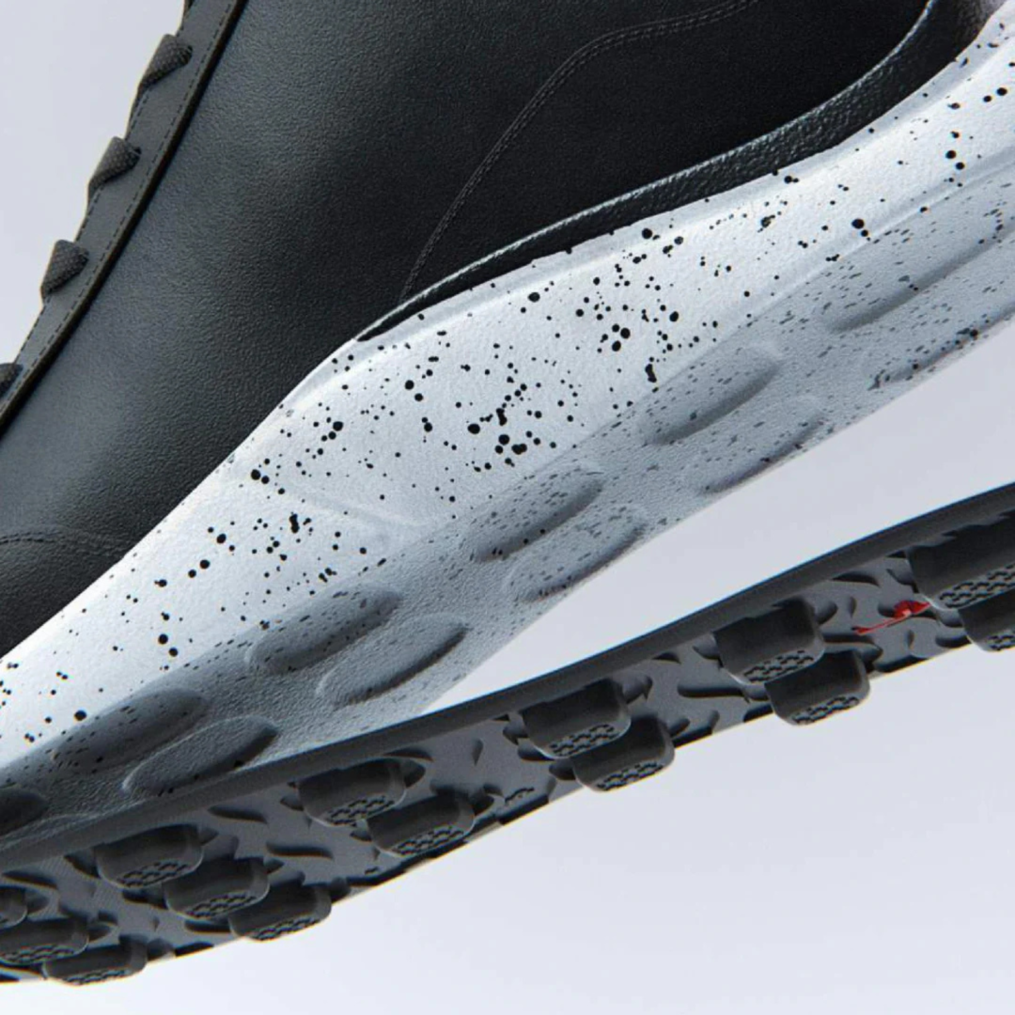 Närbild på en svart GNL-sko med vit sula med svart stänkmönster – visar teknologiskt avancerad dämpning.