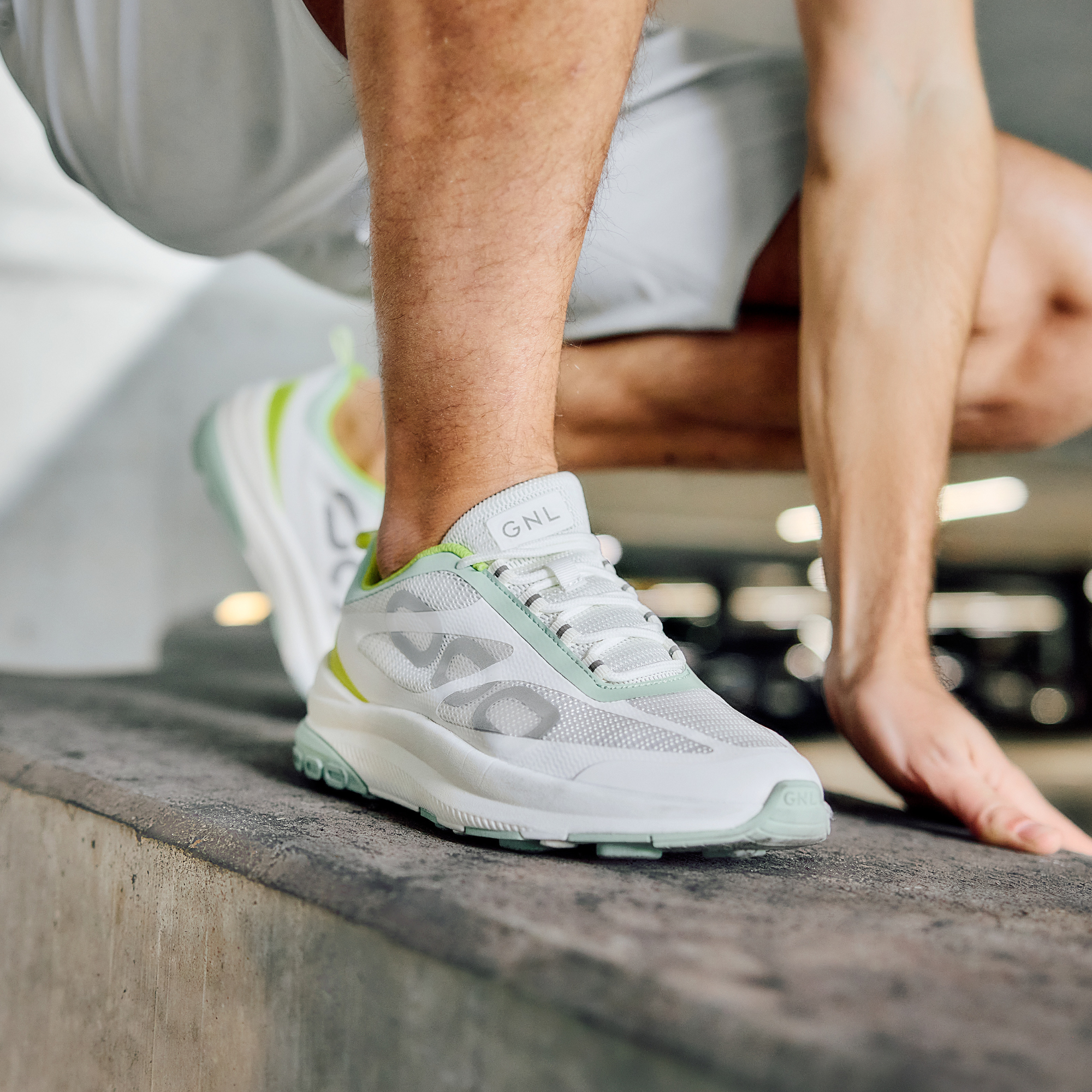 Person squatting, wearing light green shoes with GNL logo on the tongue.