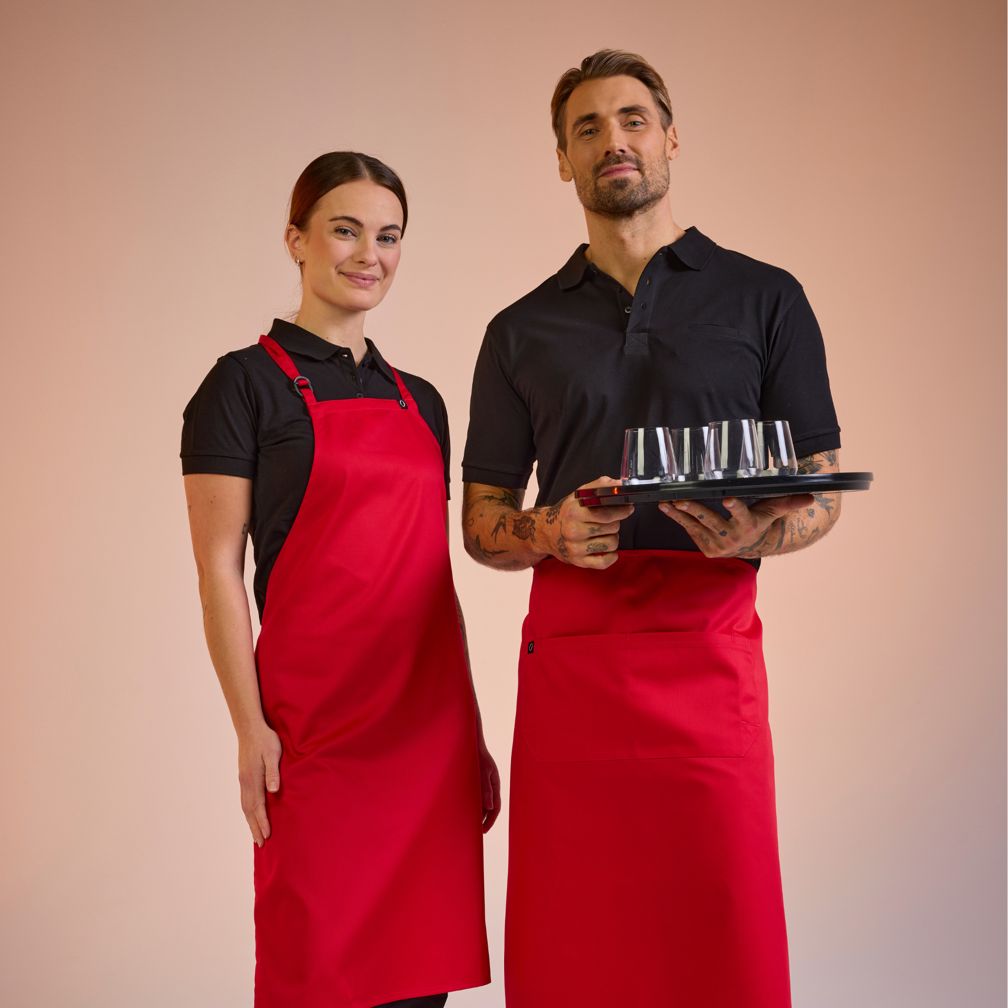 Frau und Mann in Servierkleidung von South West mit roten Schürzen – Link zum Anklicken.
