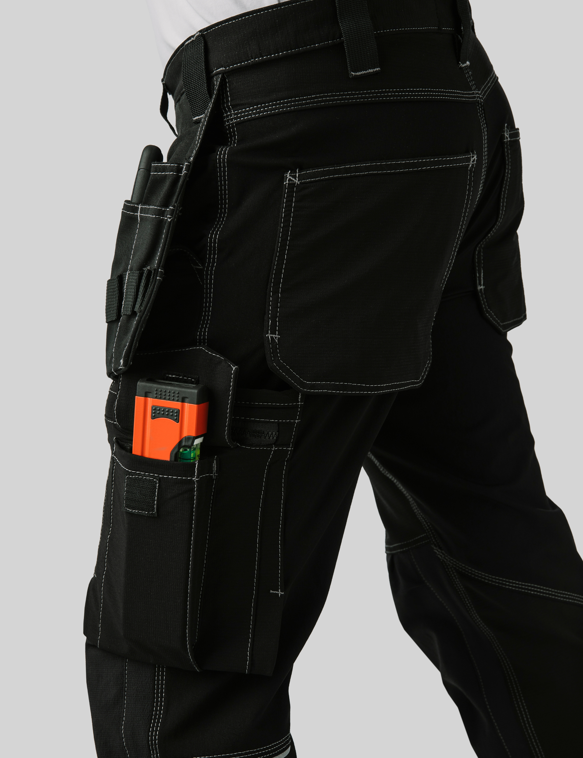 Nahaufnahme einer schwarzen Arbeitshose mit sichtbaren Werkzeugen in den Taschen – illustriert praktische Details und langlebiges Design.
