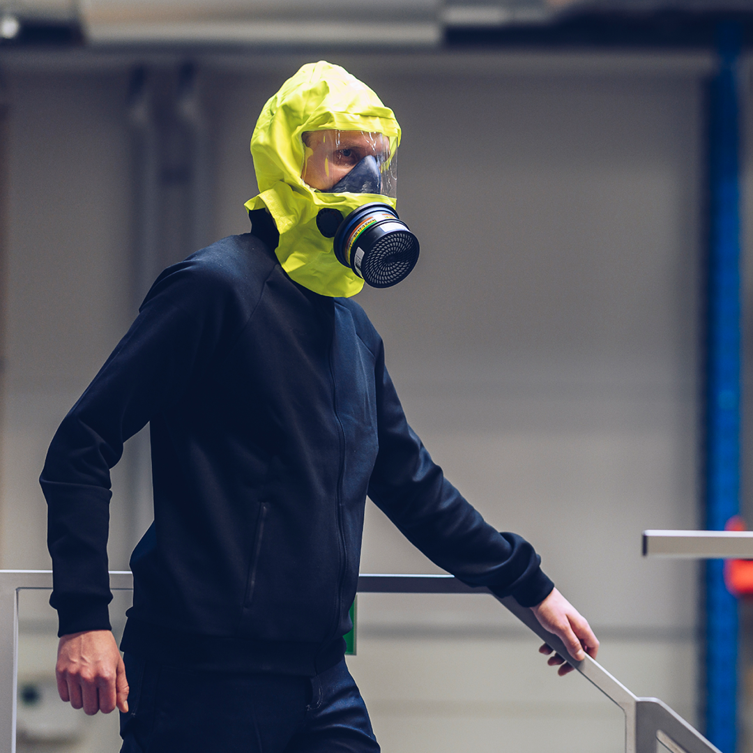 Ein Mann in Arbeitskleidung und gelber Fluchthaube